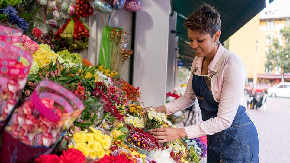 Portrait of a happy female florist organizing flowers at the stand - small business concepts.