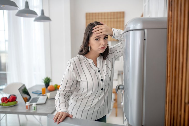 Unhappy woman next to fridge