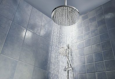 Low angle of running water from shower head in a cool coloured shower.