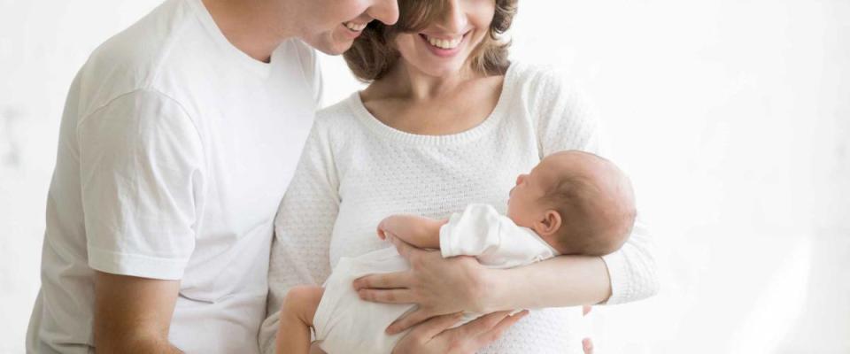 Portrait of young happy man and woman holding newborn cute babe