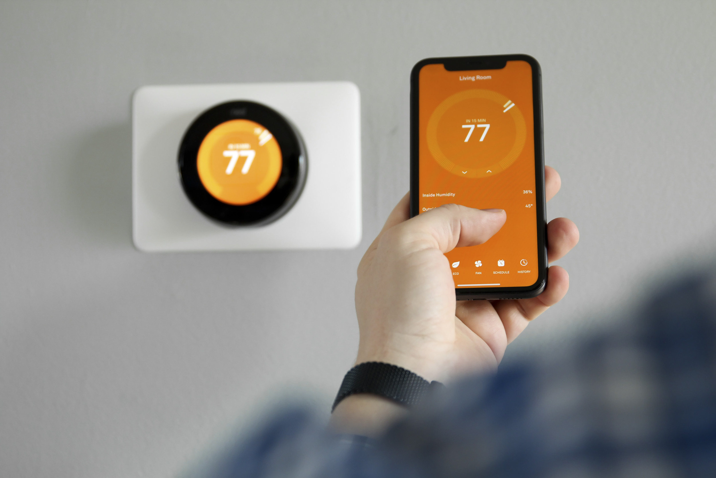A smart thermostat being used with phone.