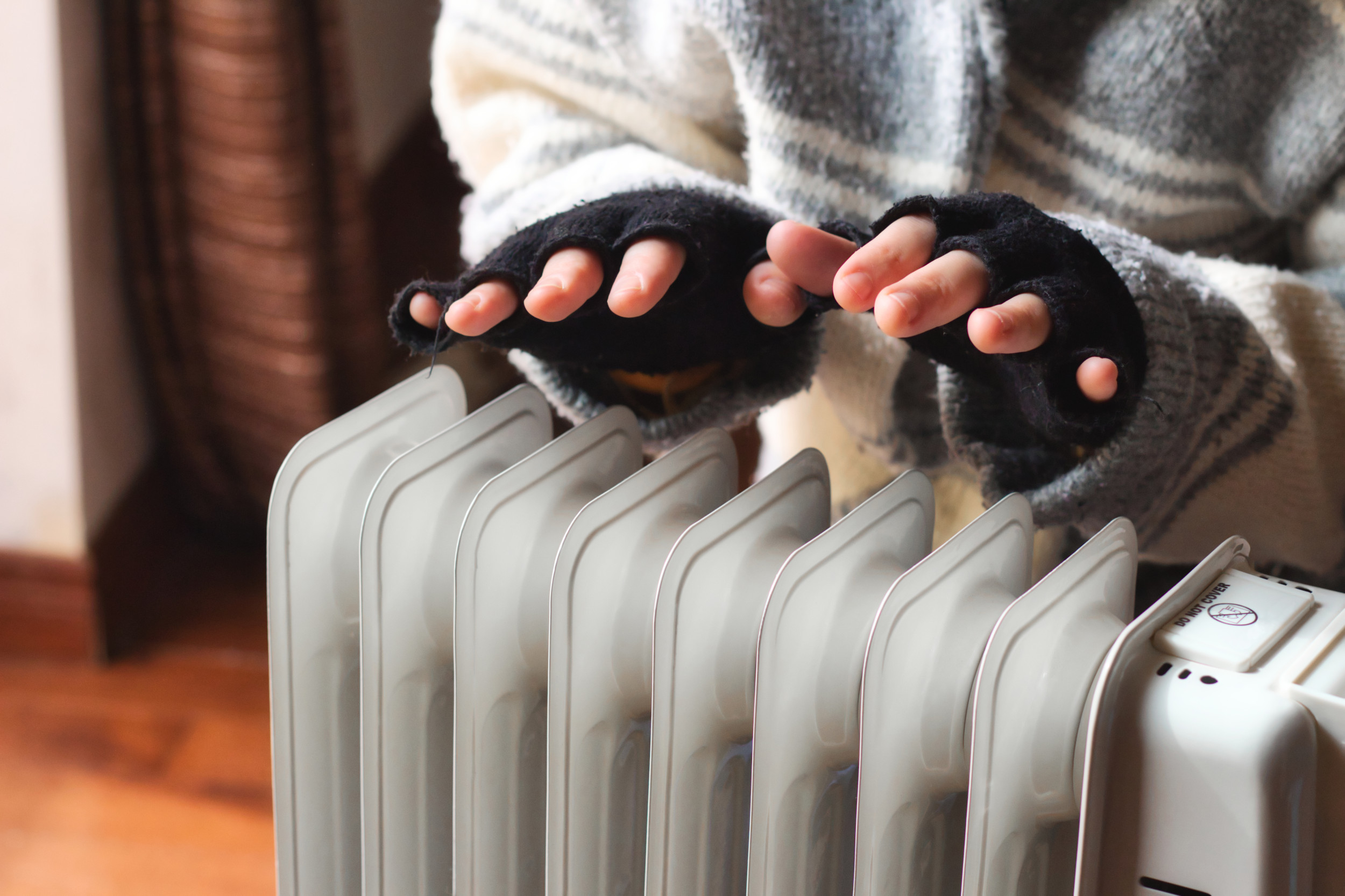 Person warming hands over portable heater.