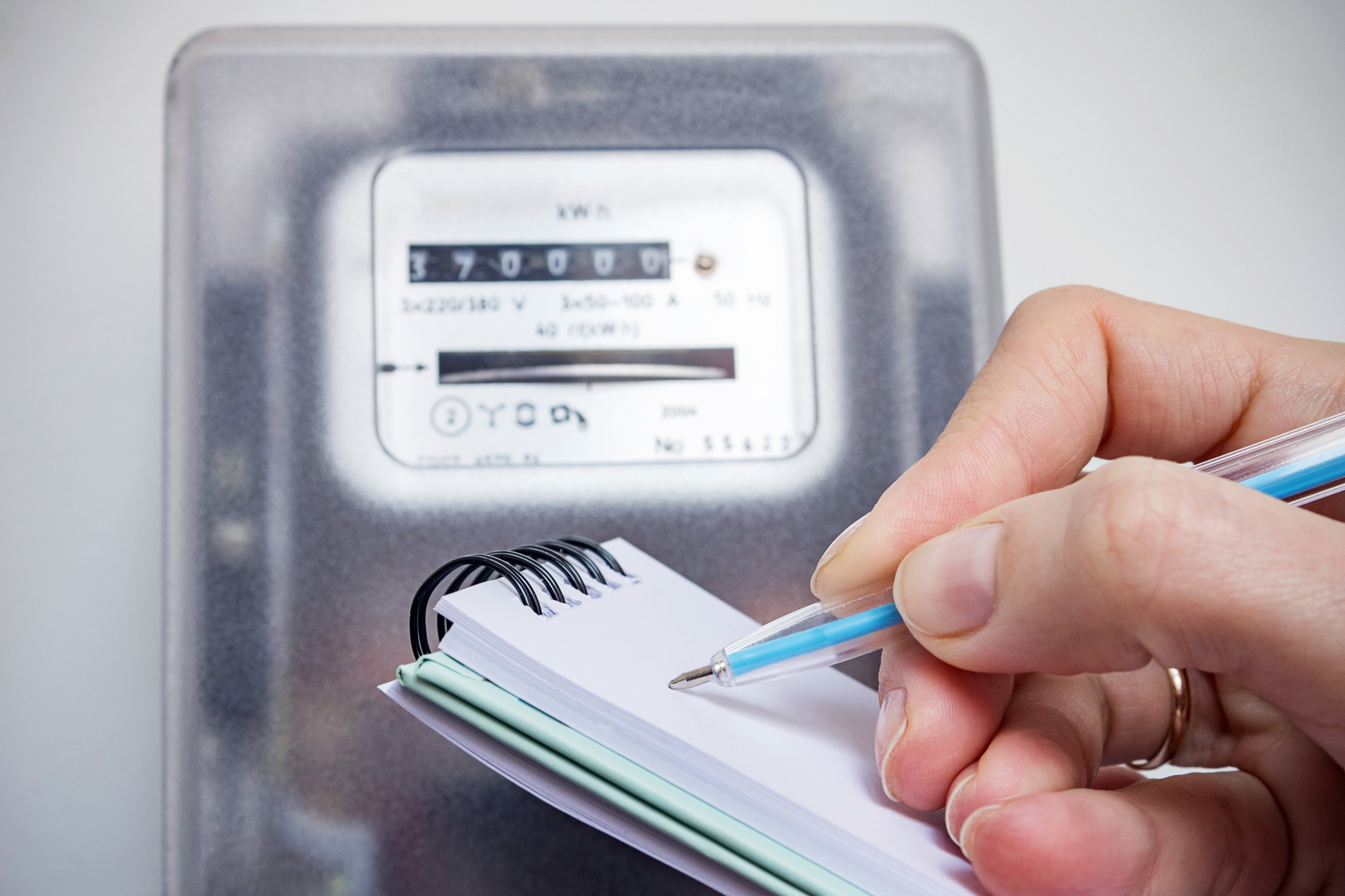 Person writing down electricity meter readings.