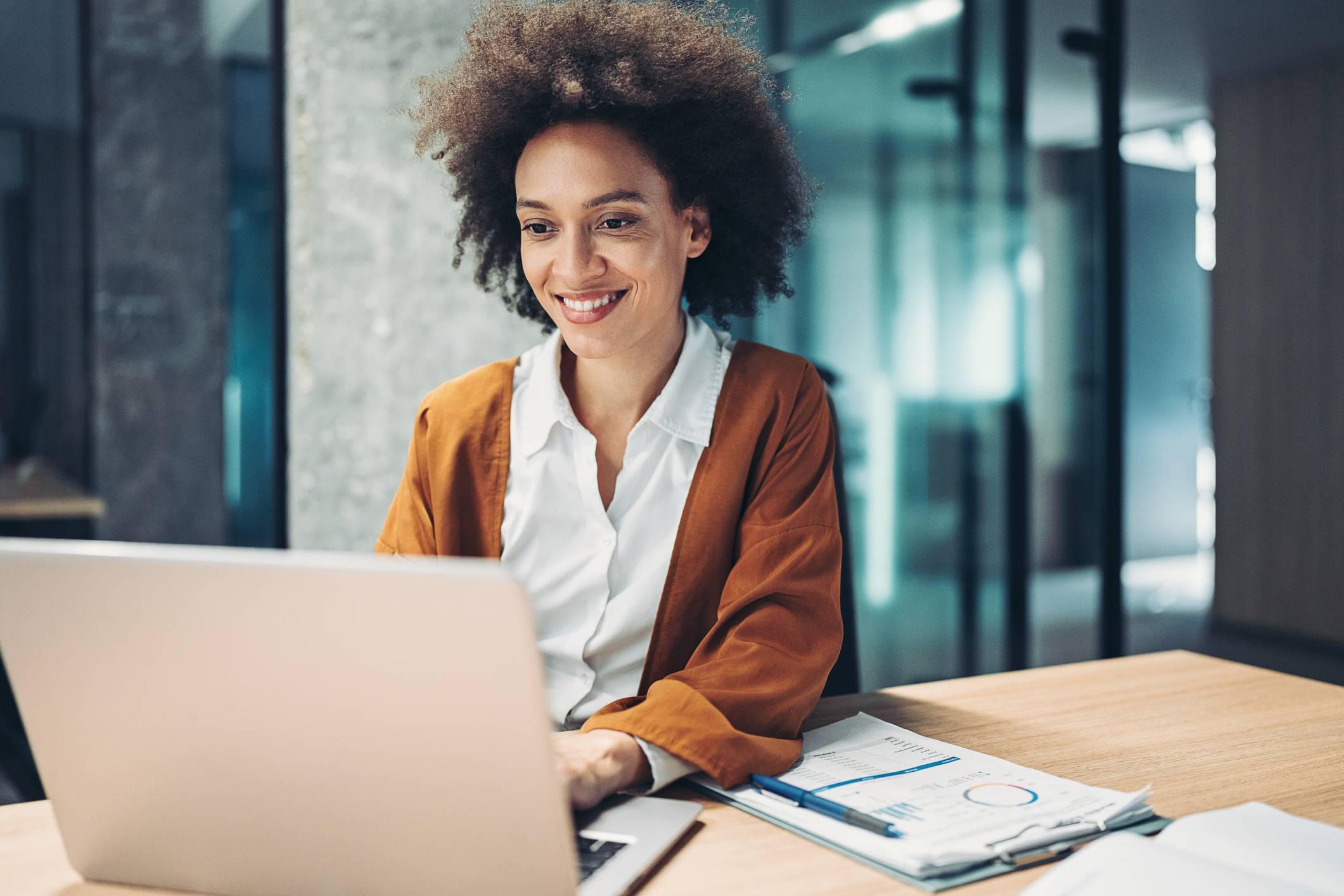 A smiling person at a laptop.